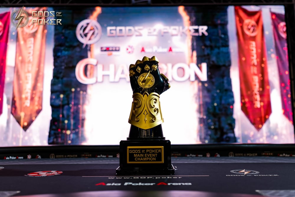 Golden gauntlet-shaped trophy stands on a stage before a screen displaying 'CHAMPION'.