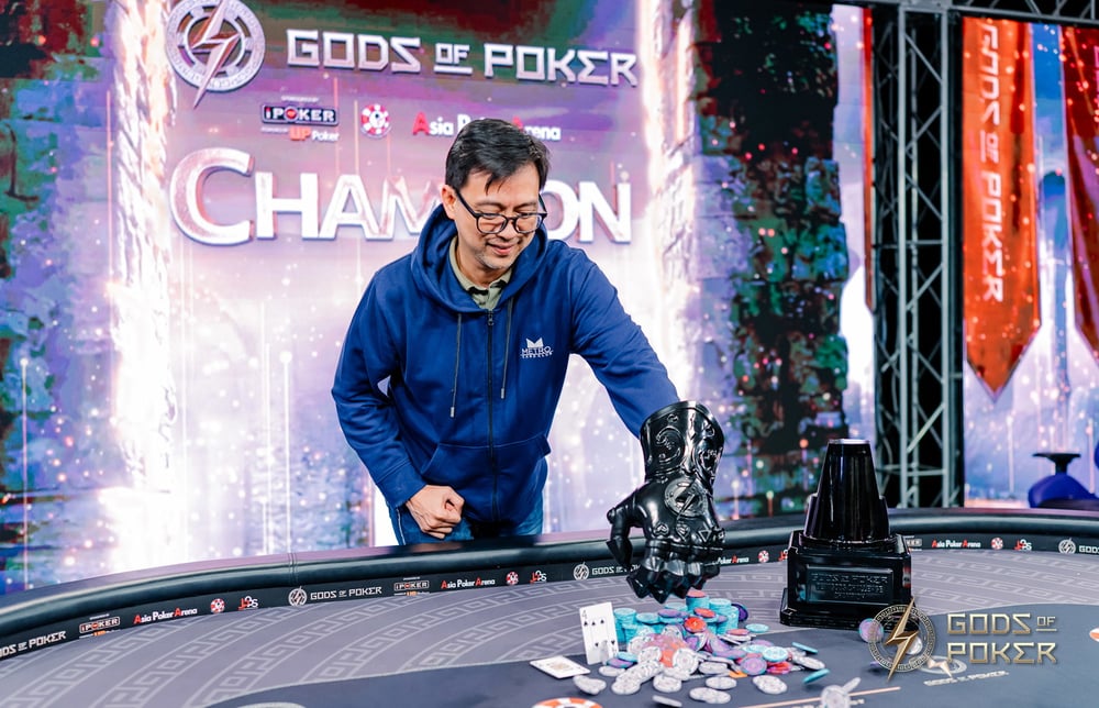Smiling poker champion collects chips and money from the table at "Gods of Poker."