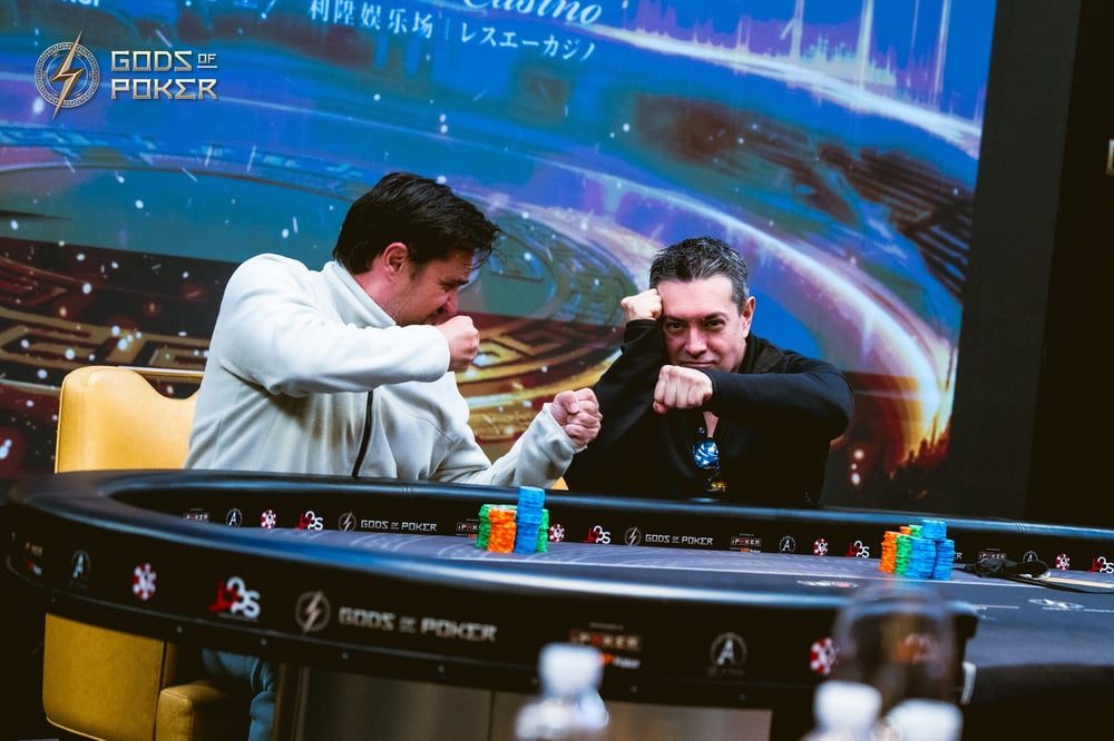 Two poker players fist-bump across a table during a competitive game.